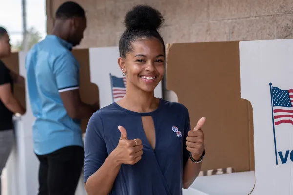 Woman at the voting booth giving a thumbs up to the camera