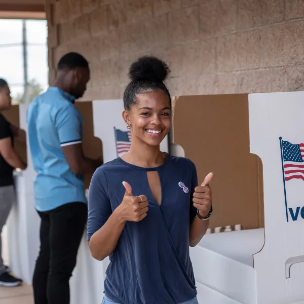 Woman at the voting booth giving a thumbs up to the camera